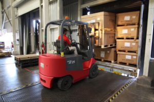 forklift unloading freight from a trailer at a logistics company loading dock